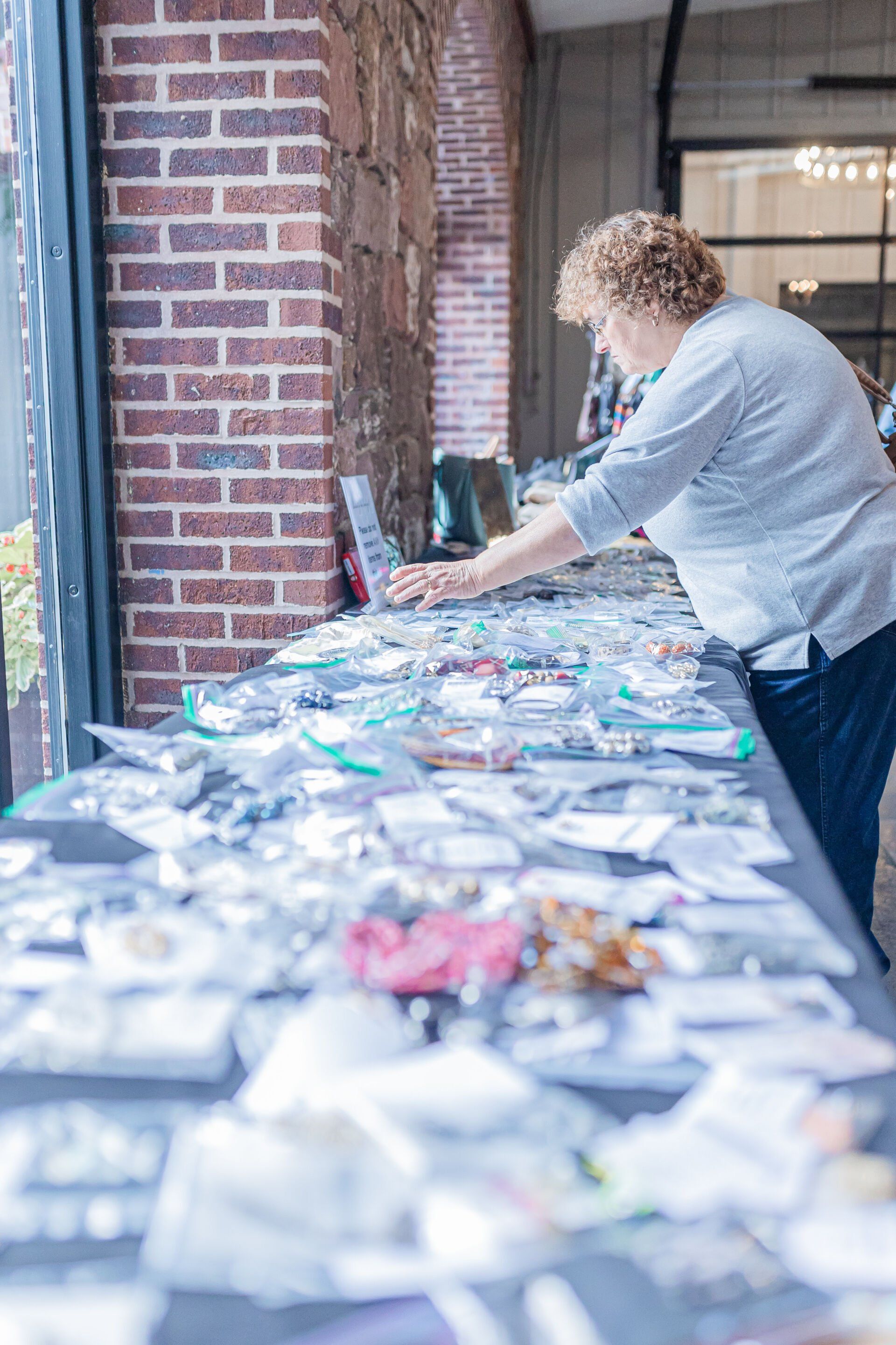 A woman is standing at a table with a lot of items on it.