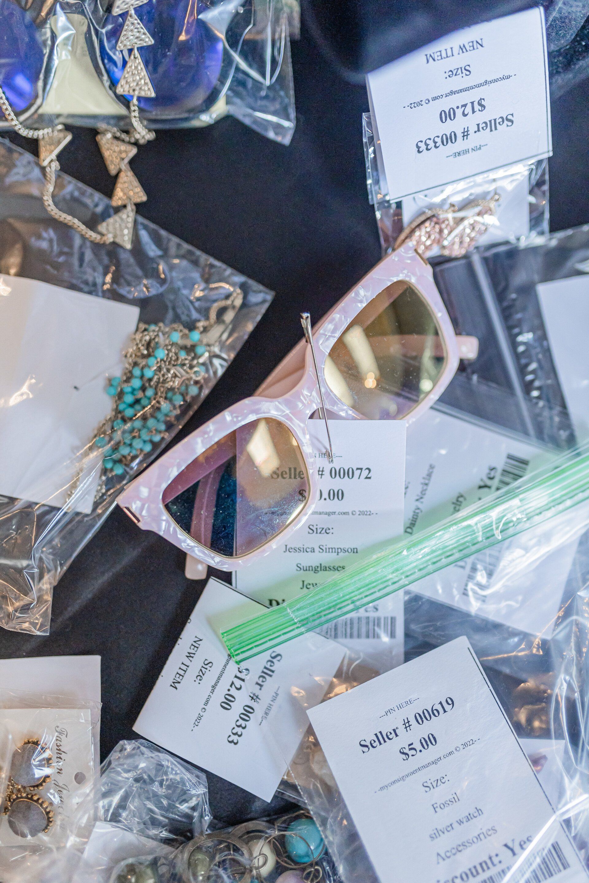 A pair of sunglasses is sitting on top of a pile of jewelry.