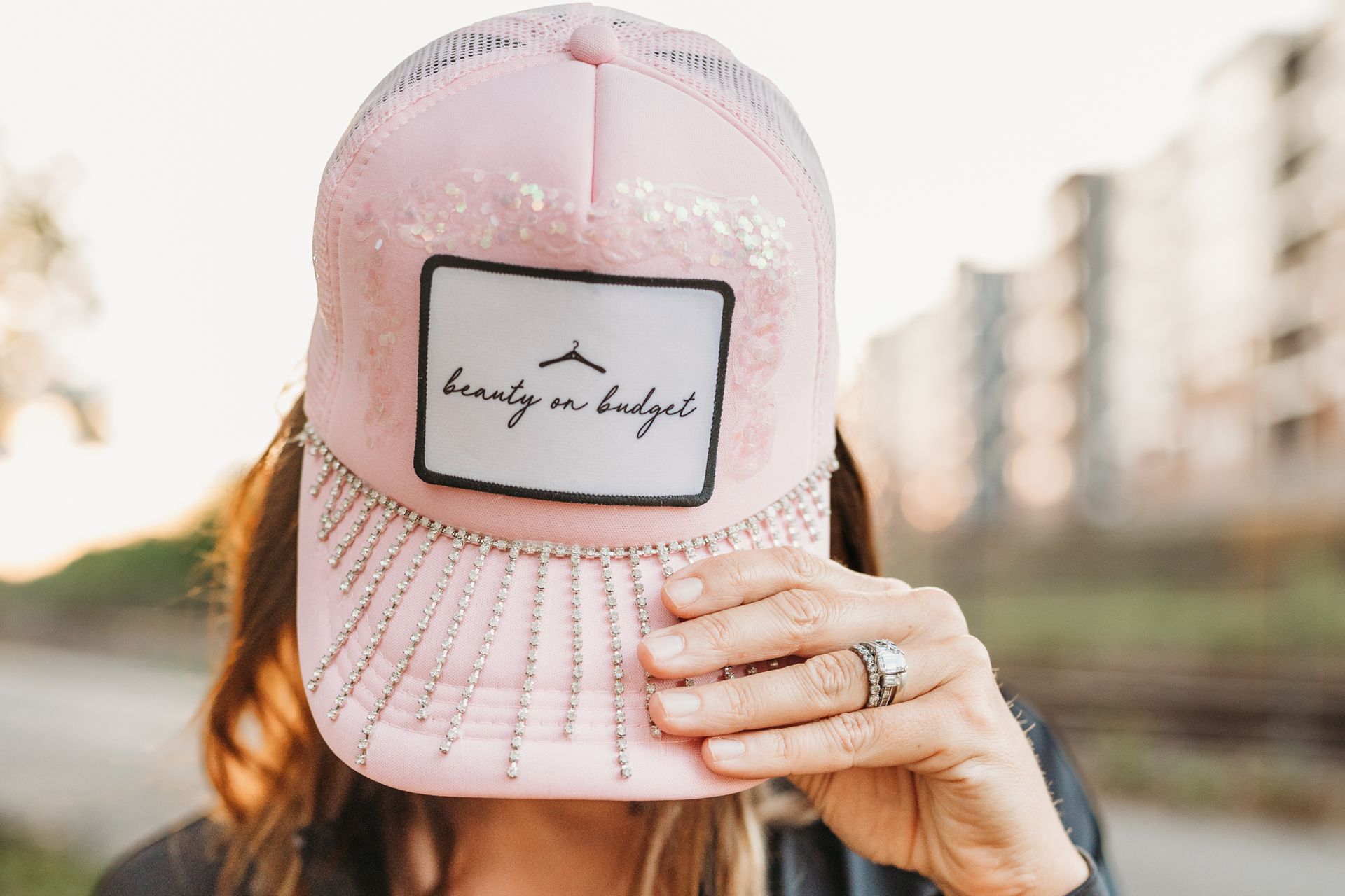 A woman is covering her face with a pink hat.