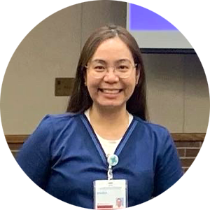A woman wearing glasses and a name tag is smiling in a circle.