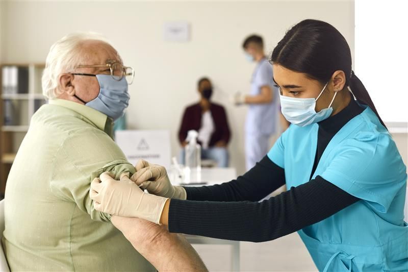 A nurse is giving an elderly man a vaccine.