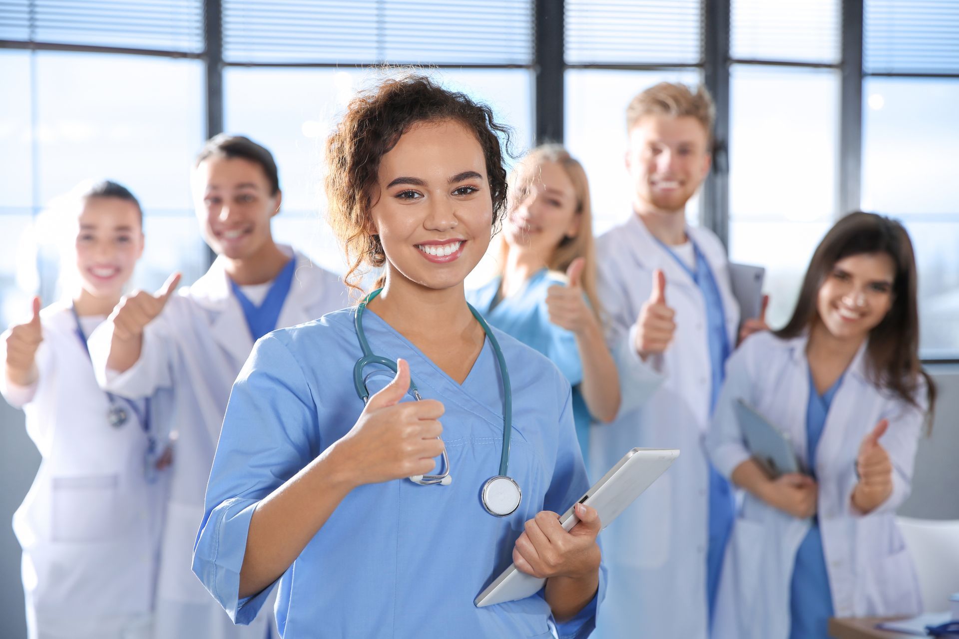 A group of doctors and nurses are giving a thumbs up.