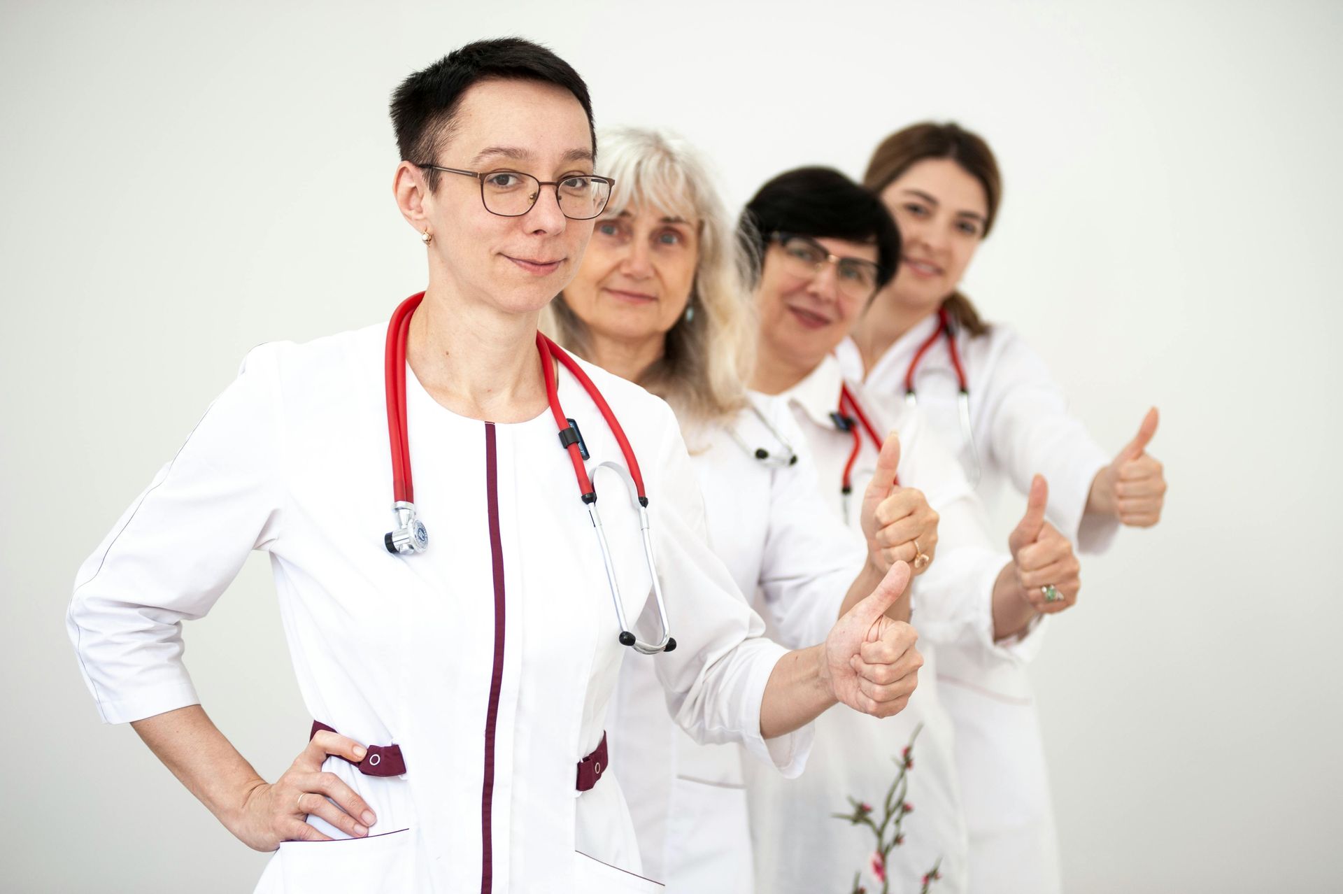 A group of doctors are standing next to each other and giving a thumbs up.