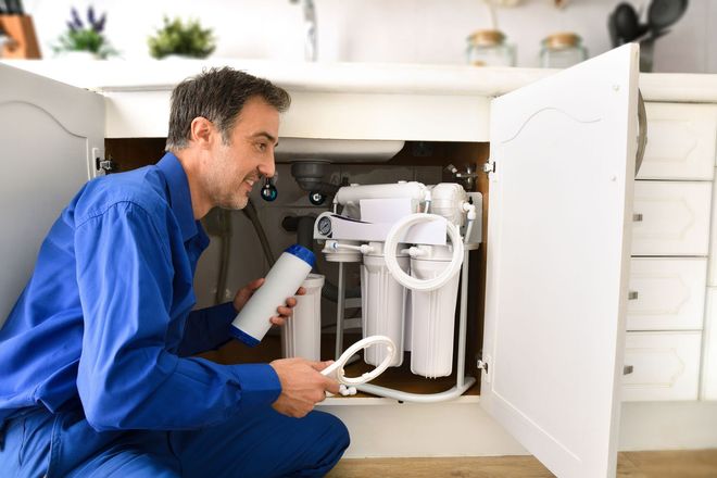 technician installing reverse osmosis equipment under