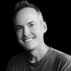 A man is smiling in a black and white photo.