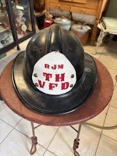 Black firefighter helmet with white patch reading 