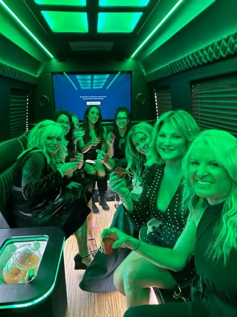 A group of women are sitting in a limo with green lights.