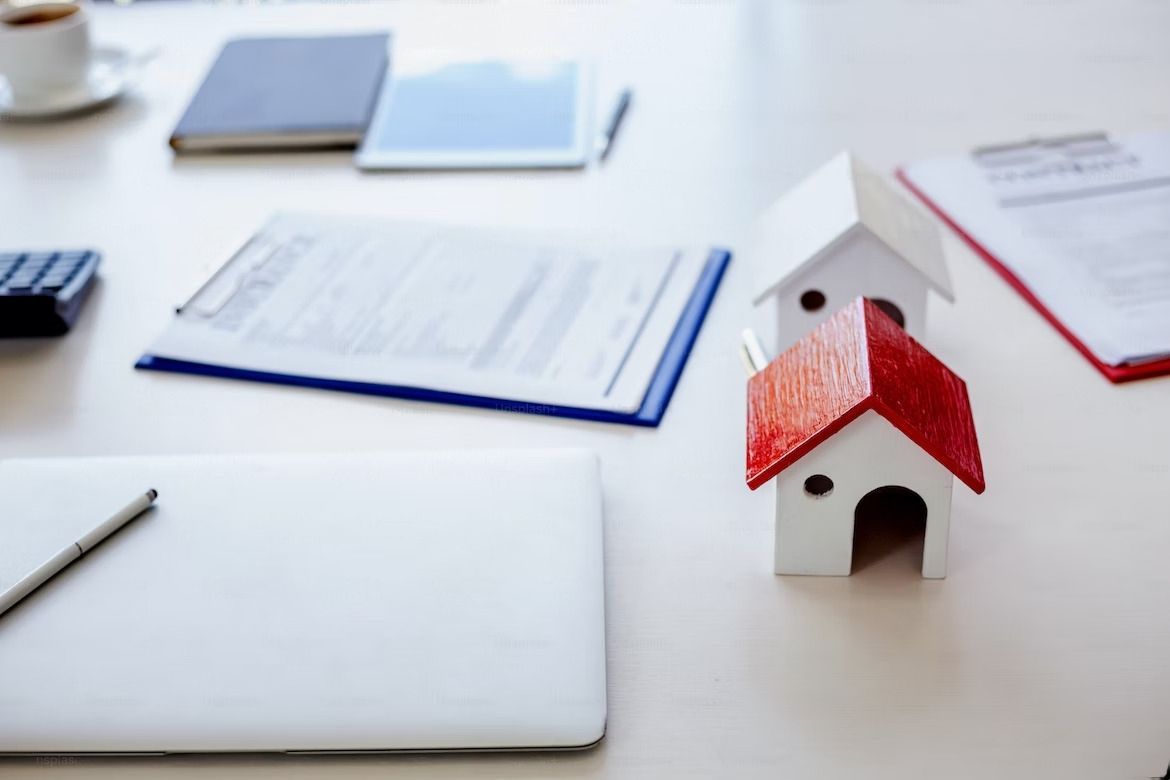 Two small houses are sitting on a desk next to a laptop.