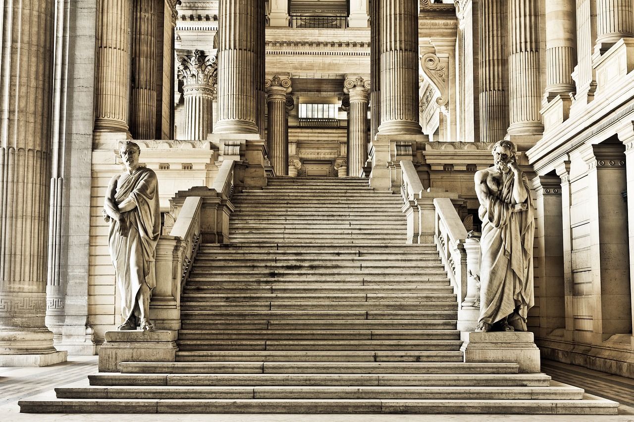 Staircase in a grand building with statues and columns. Sepia tone.