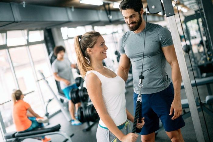 young beautiful woman doing exercises with personal trainer