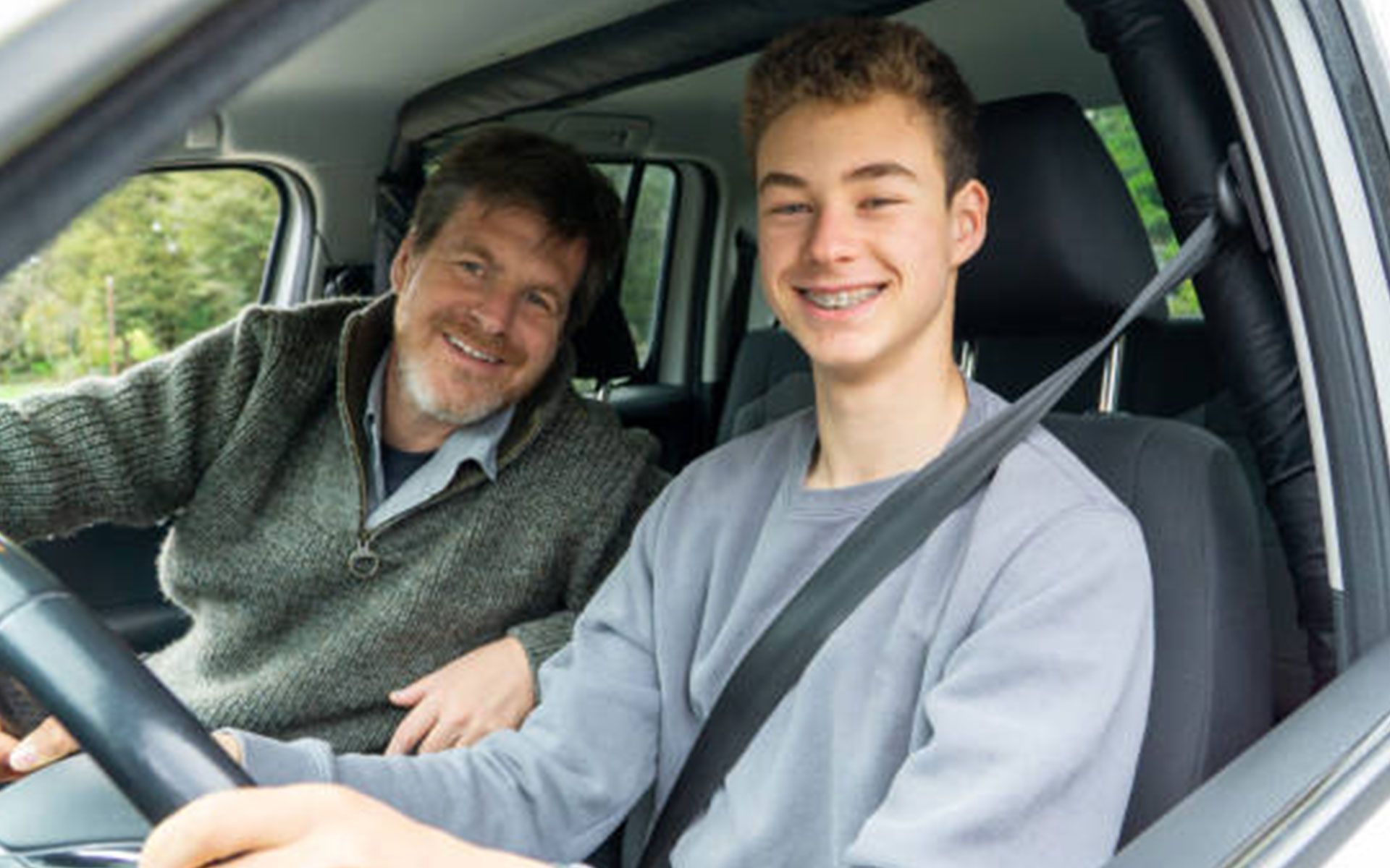 A man is teaching a young boy how to drive a car.
