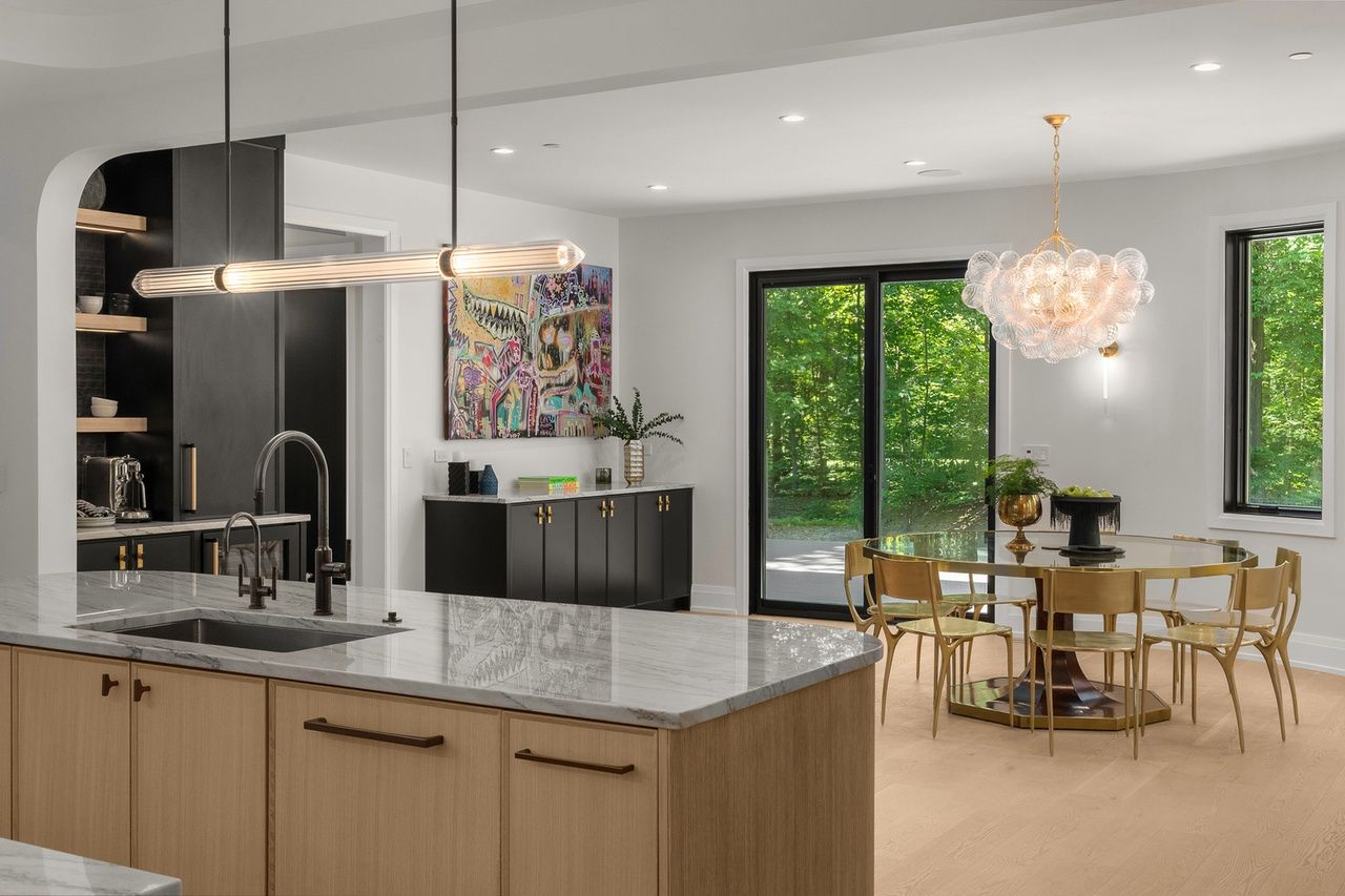 A kitchen with a sink , dining table , chairs and sliding glass doors.