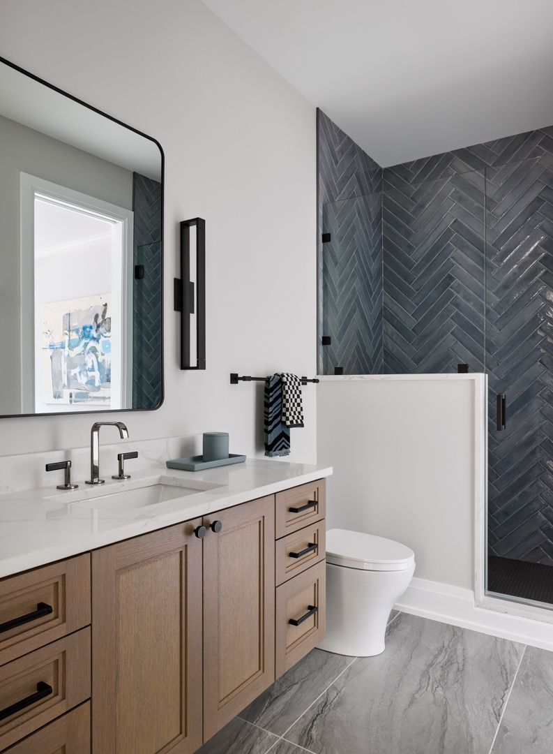 A bathroom with a toilet , sink , mirror and shower.