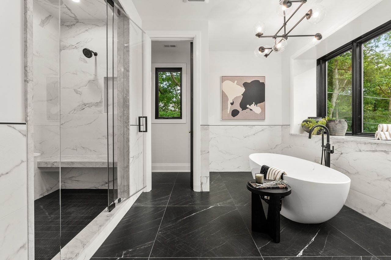 A bathroom with a tub , shower , and window.