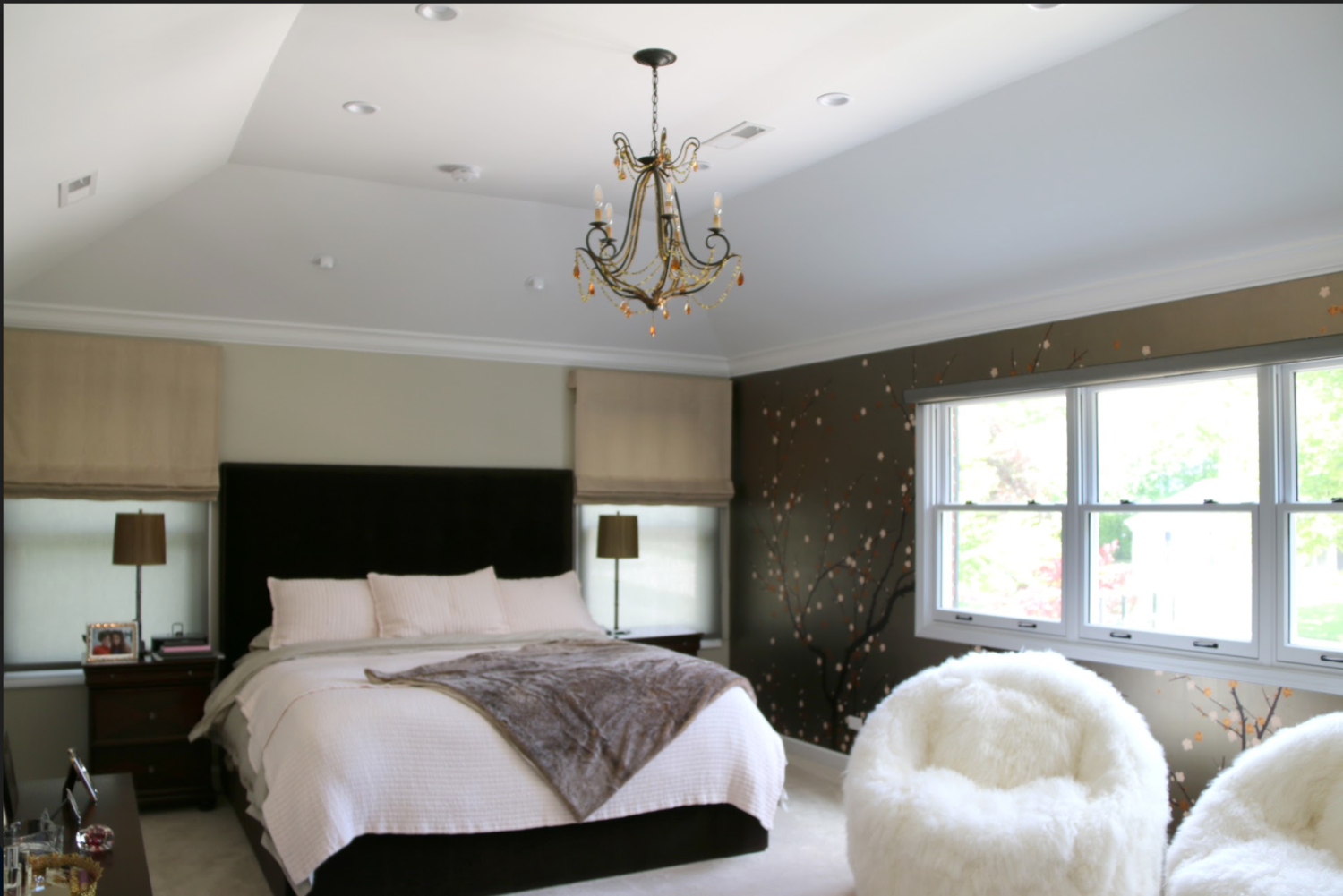 A bedroom with a large bed and two fluffy chairs