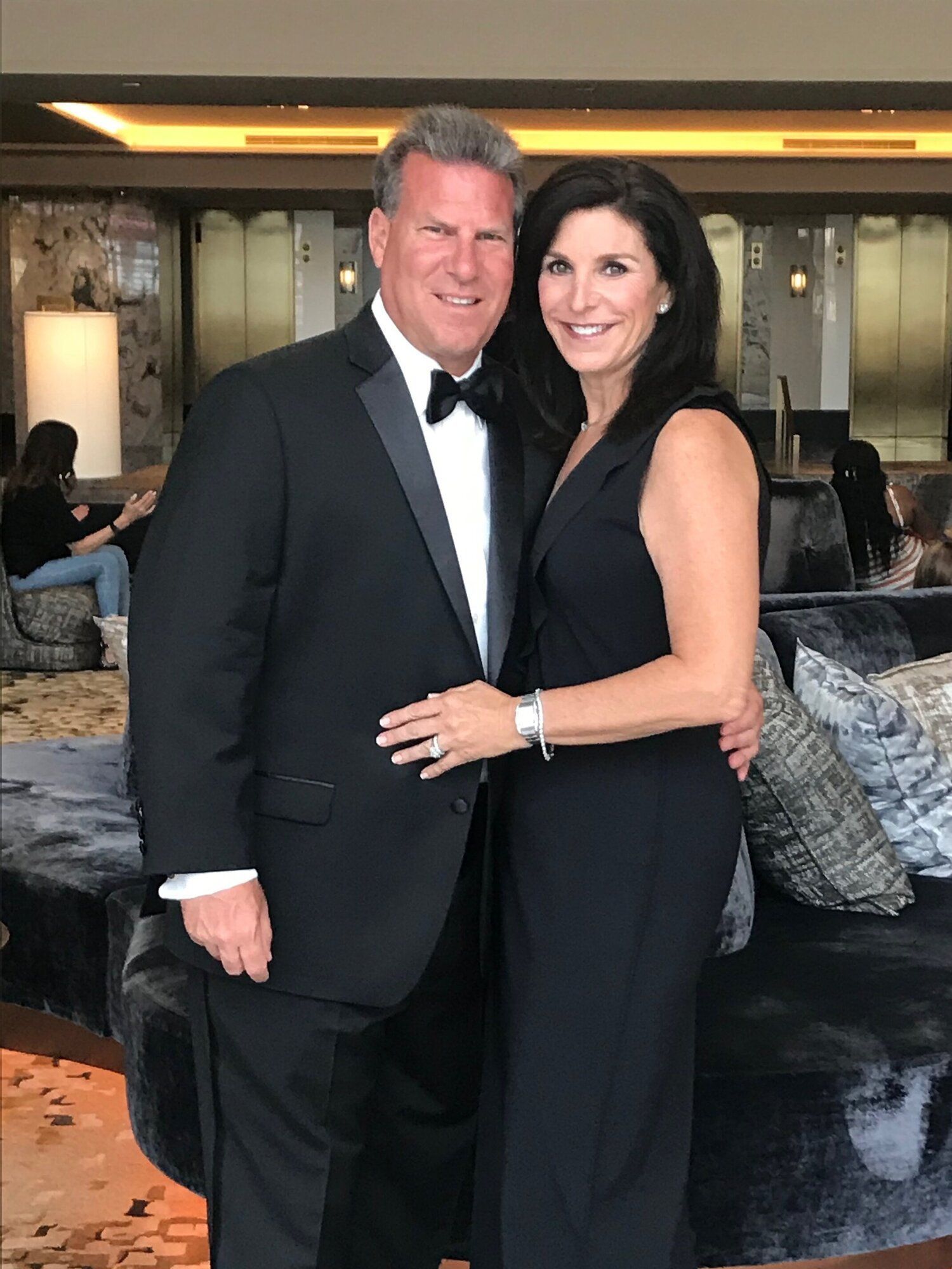 A man in a tuxedo and a woman in a black dress are posing for a picture.