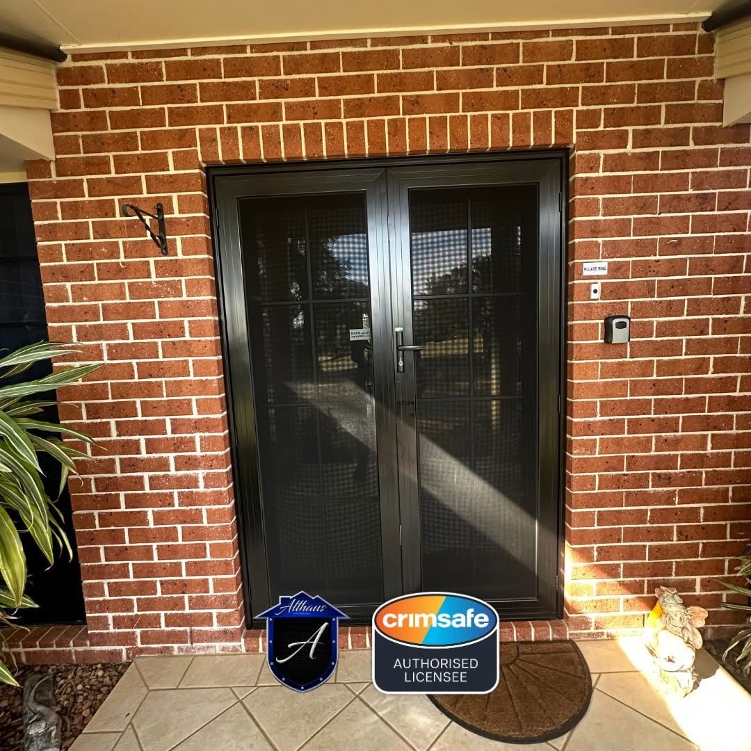 An open cream-colored door with a stained-glass floral oval revealing a black metal security screen door, interior view.
