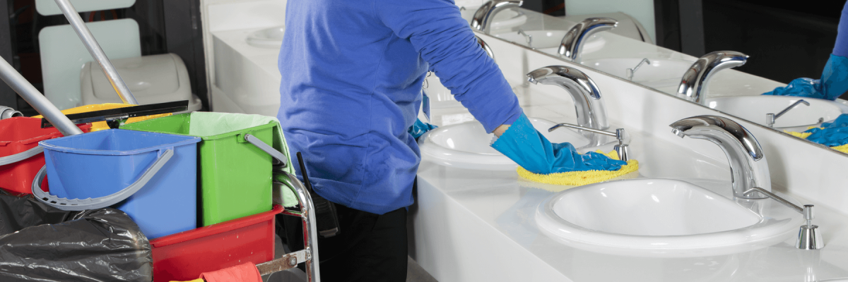 Lady wearing gloves wiping counter in business restroom