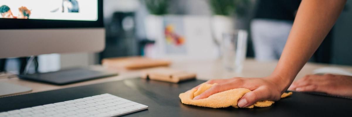 A person is cleaning a desk with a cloth.