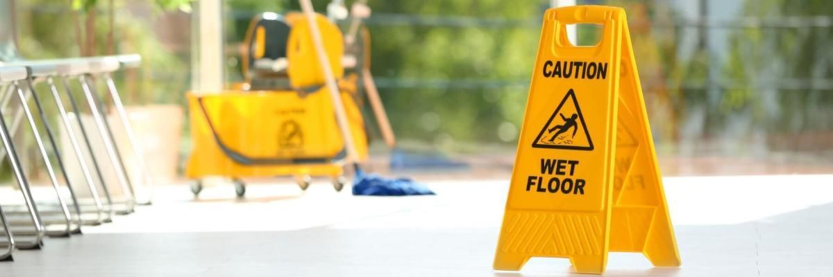 A yellow wet floor sign is sitting on a concrete floor.