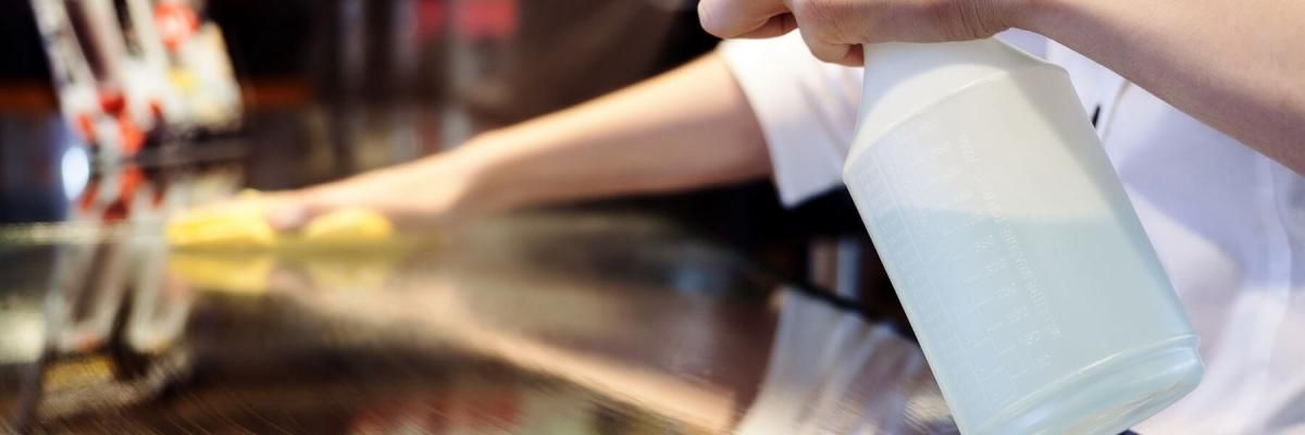 A person is cleaning a counter with a spray bottle.