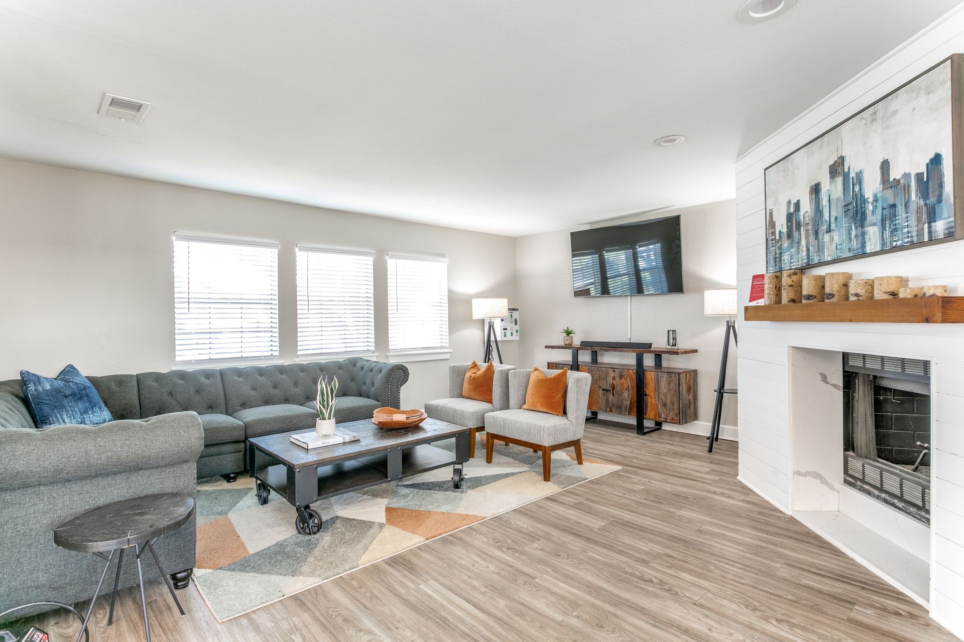 Living room with gray sofa, armchairs, fireplace, and colorful rug.