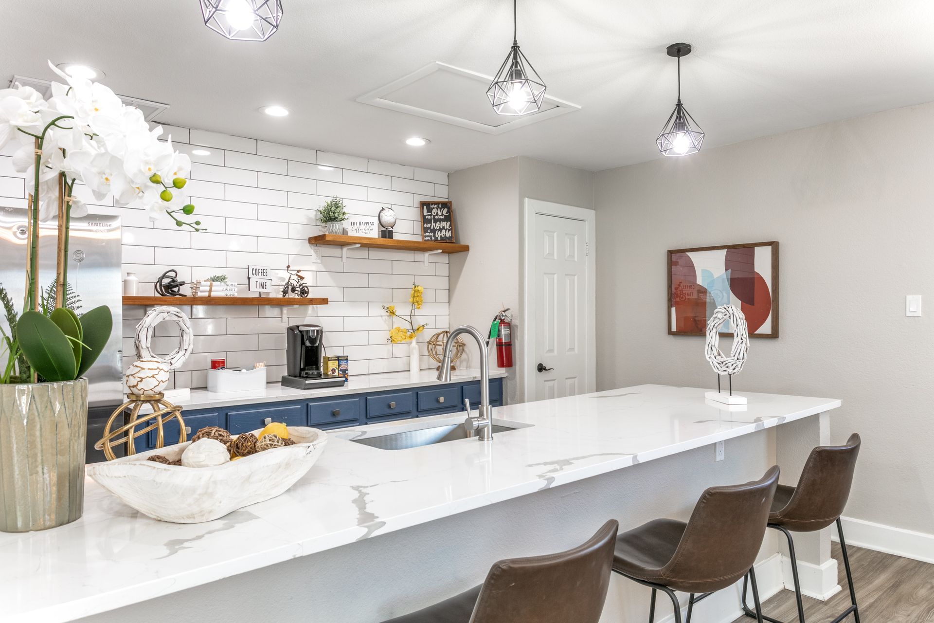 Modern kitchen with white countertop, blue cabinets, and decorative accents.