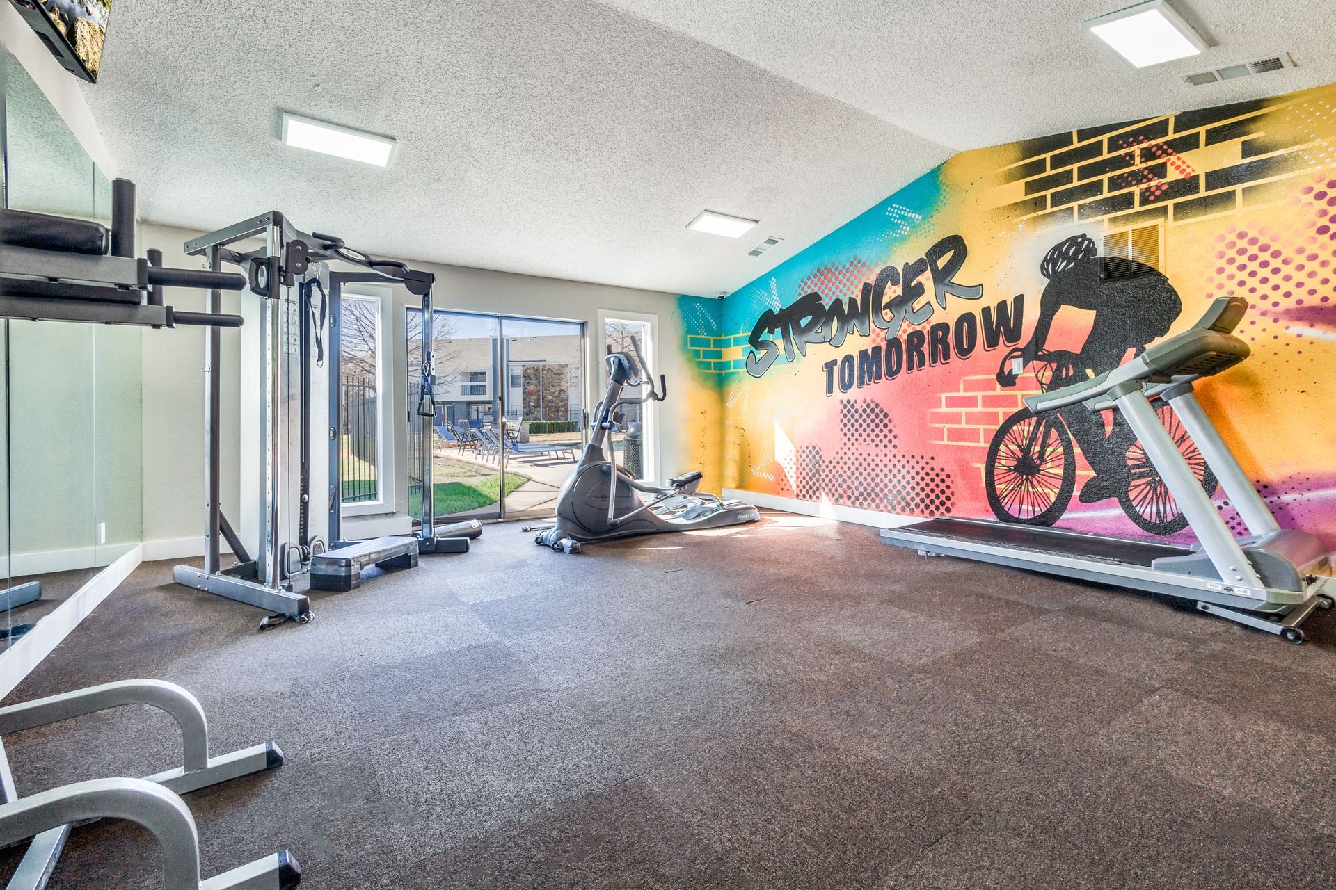 Gym with exercise machines, graffiti wall art featuring a cyclist and the words 