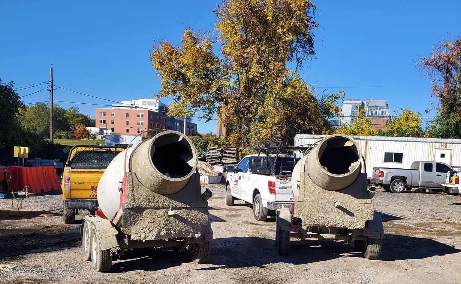 two concrete mixers are parked next to each other in a parking lot .