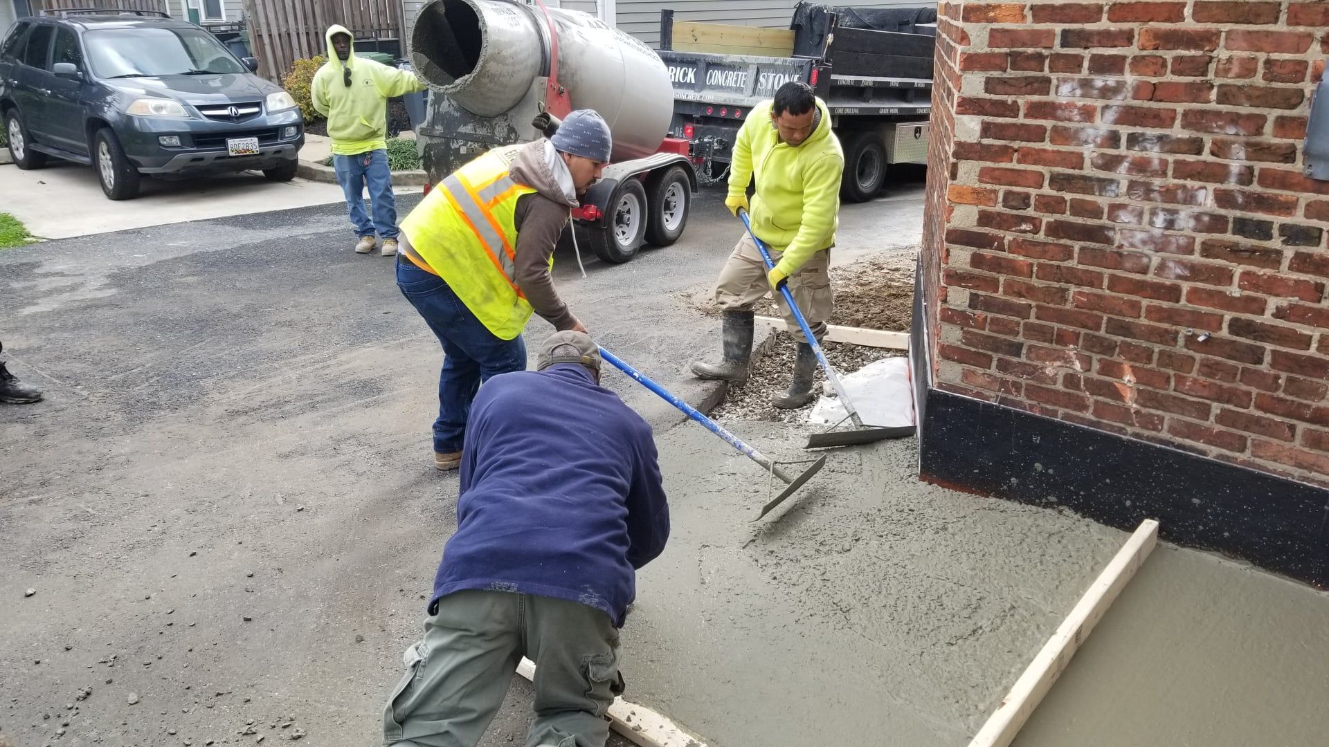 a group of construction workers are working on a concrete driveway .