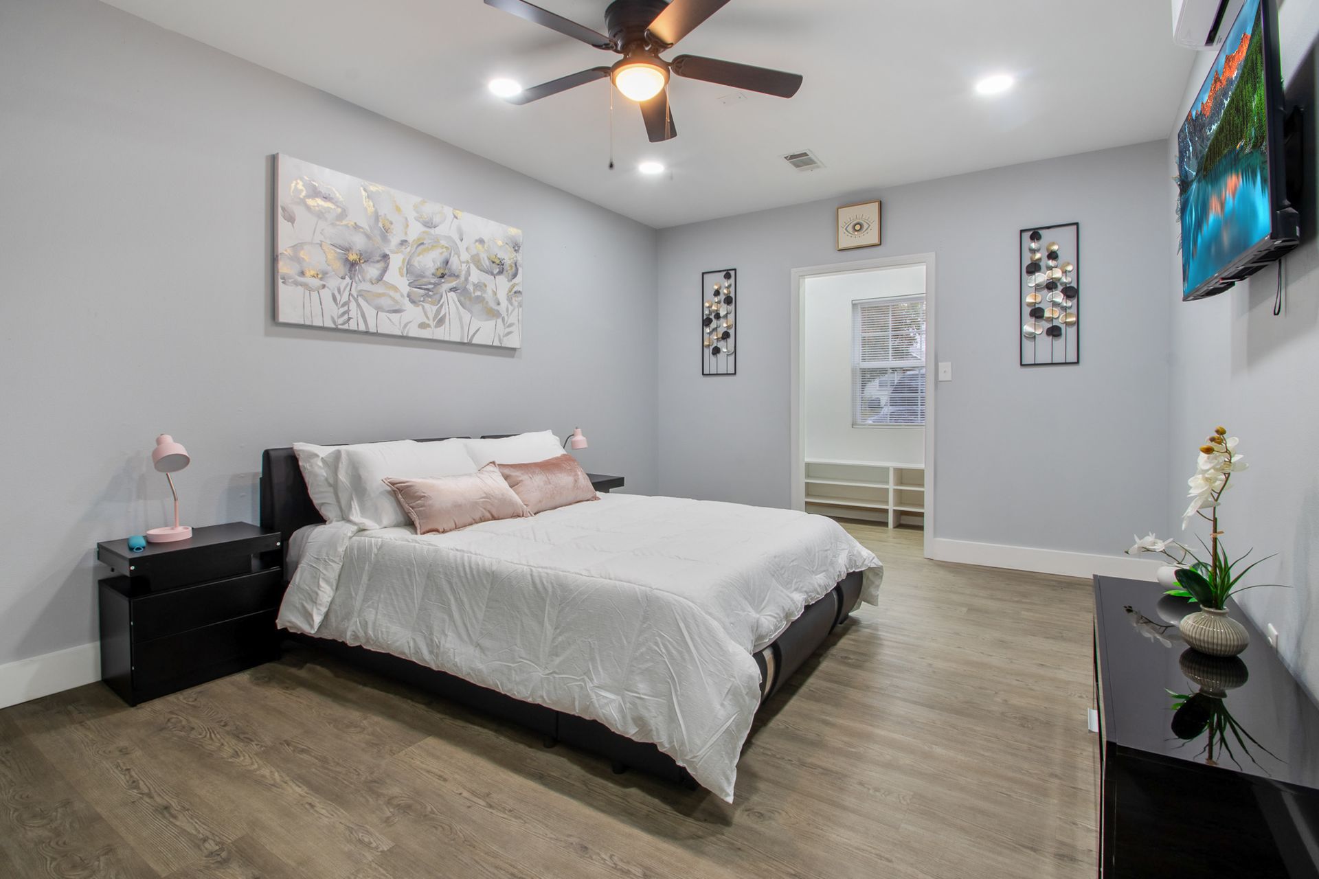 A bedroom with a bed , nightstand , television and ceiling fan.