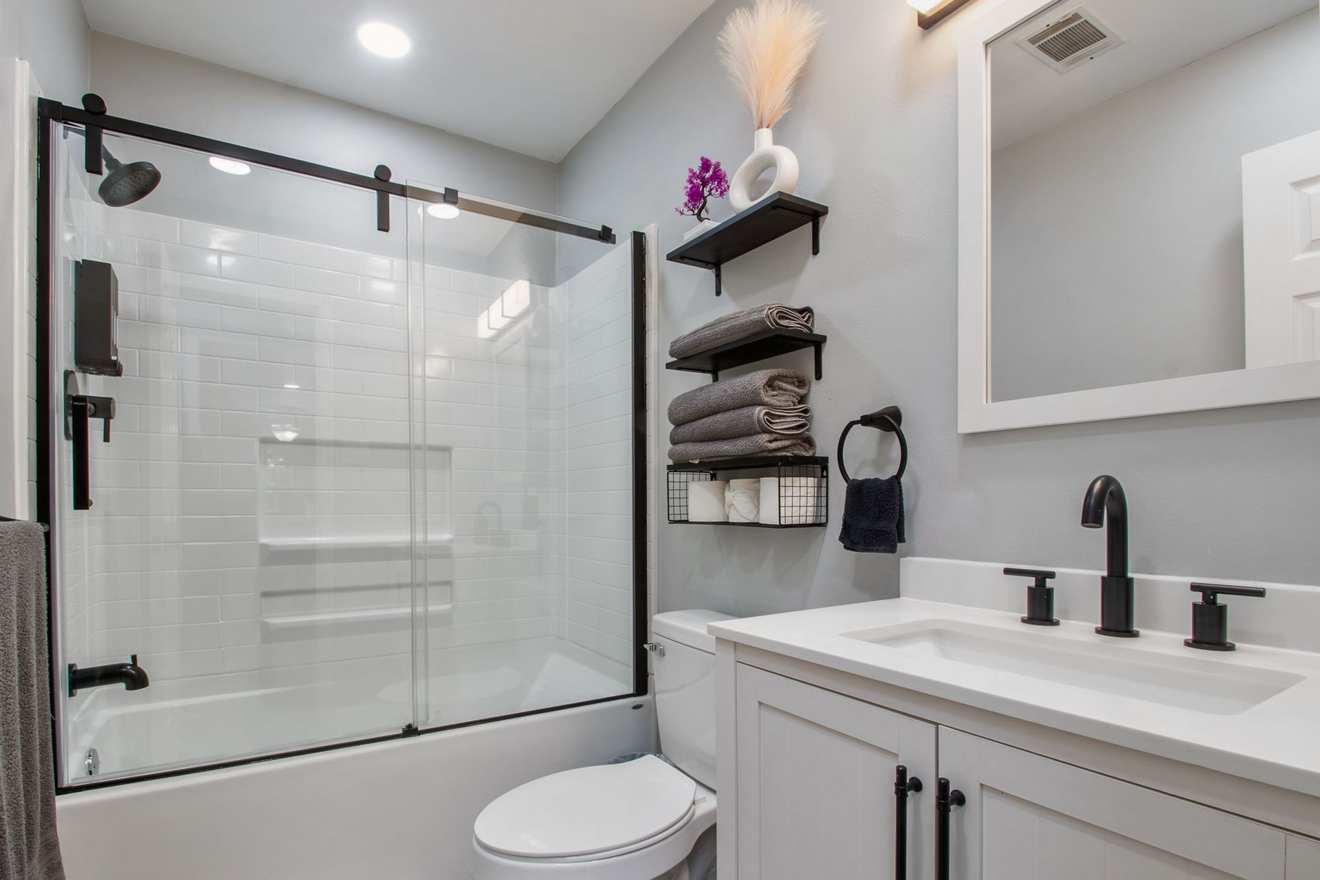 A bathroom with a toilet , sink , shower and mirror.