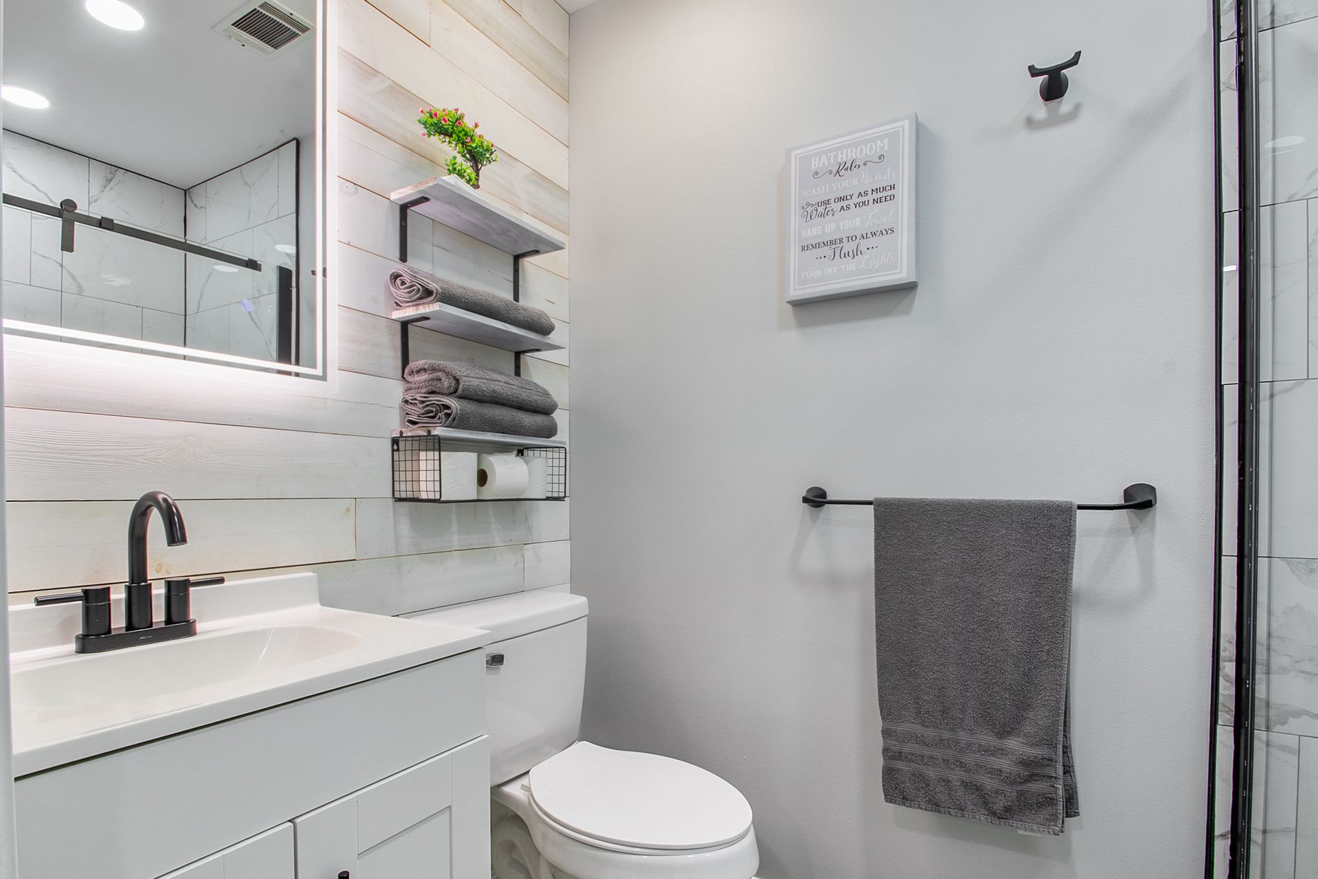 A bathroom with a toilet , sink , mirror and shower.