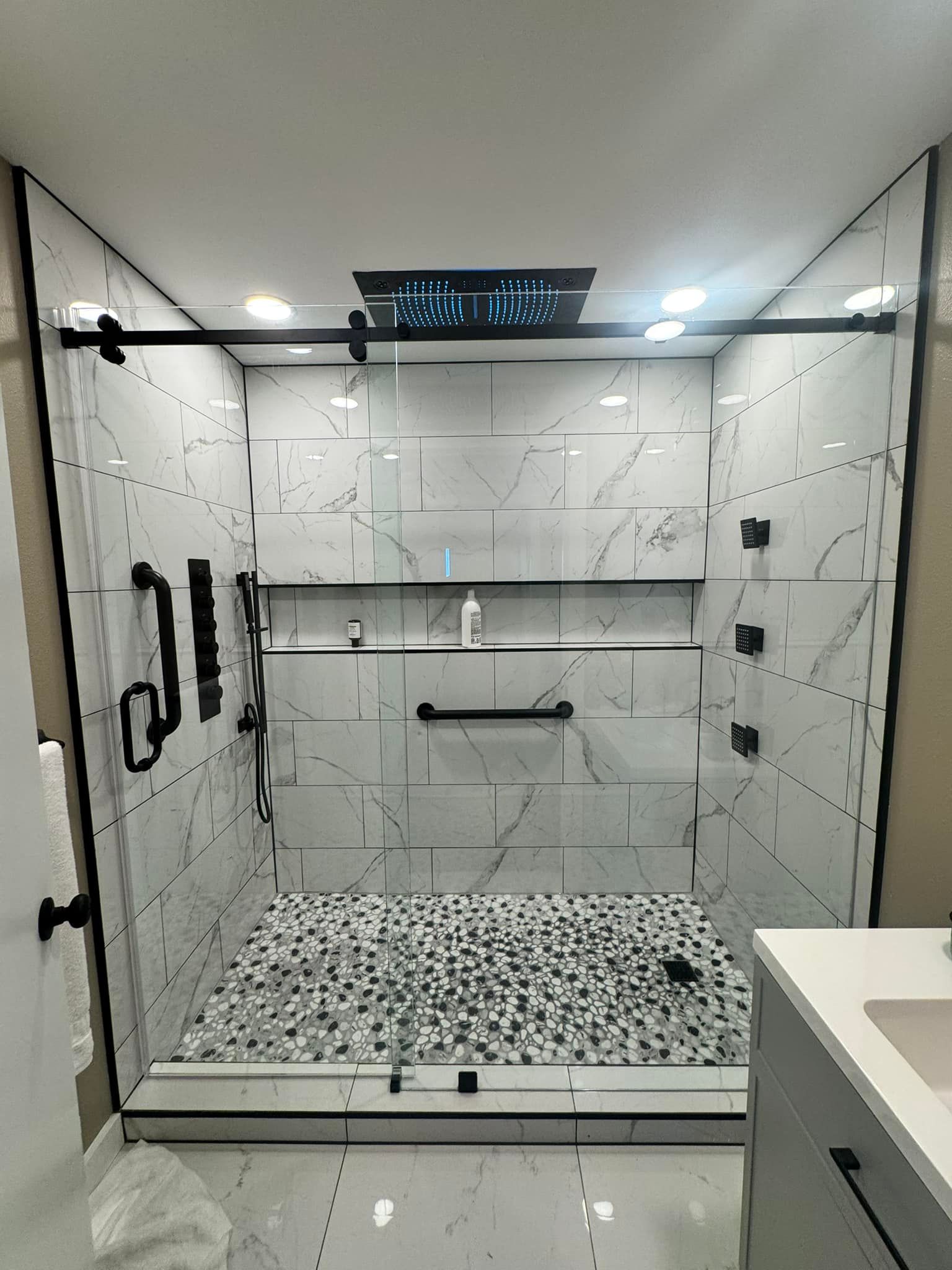 A bathroom with a walk in shower and a sink.