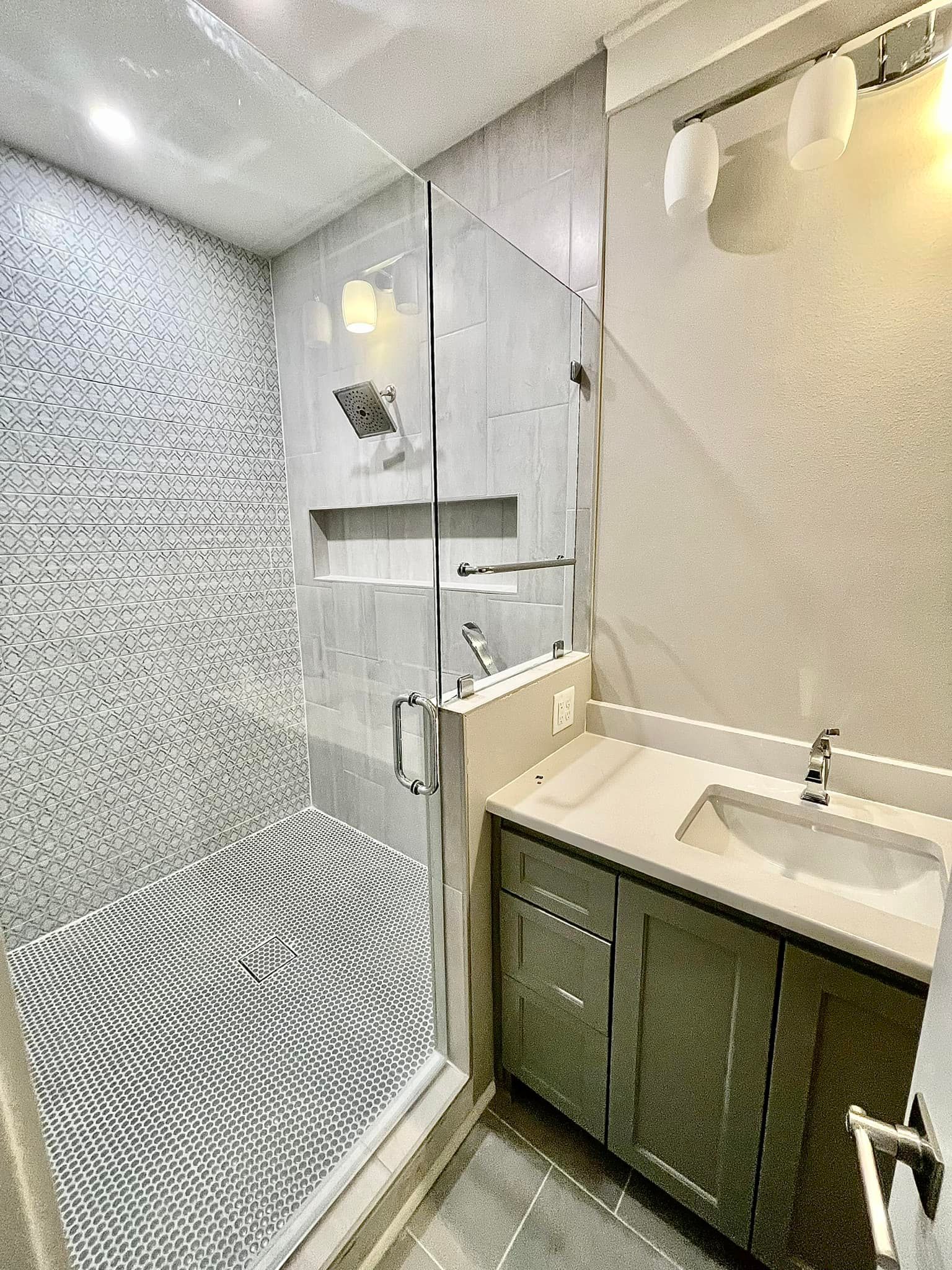 A bathroom with a walk in shower , sink and mirror.