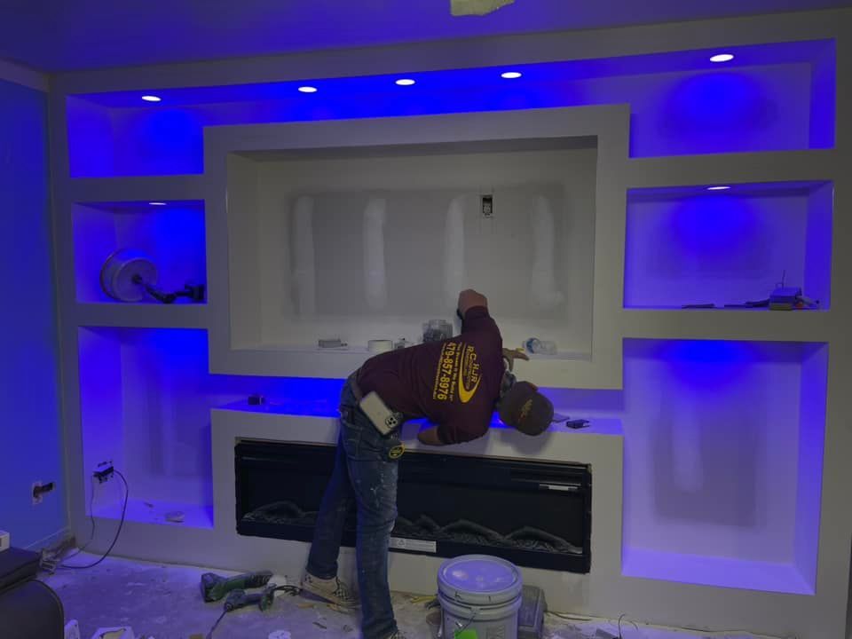 A man is working on a fireplace in a living room.