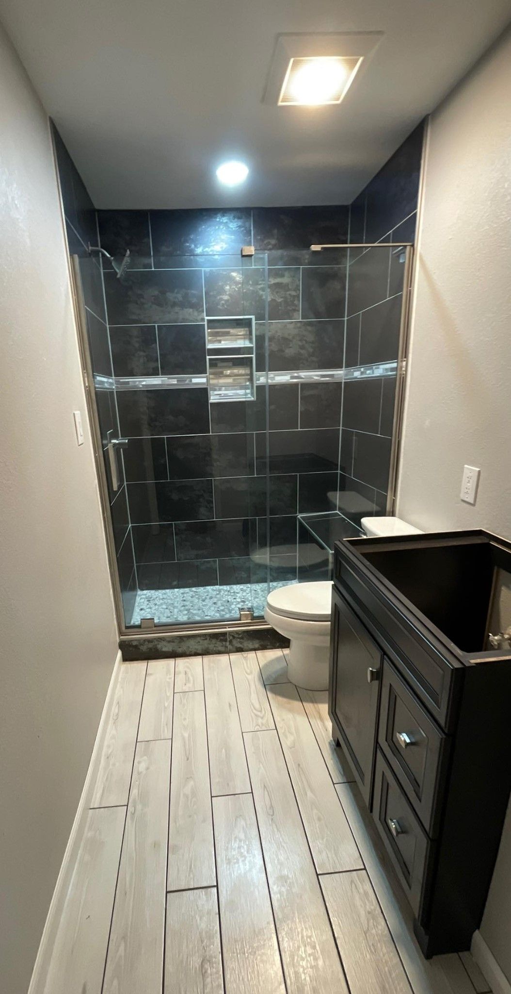 A bathroom with a toilet , sink and shower.