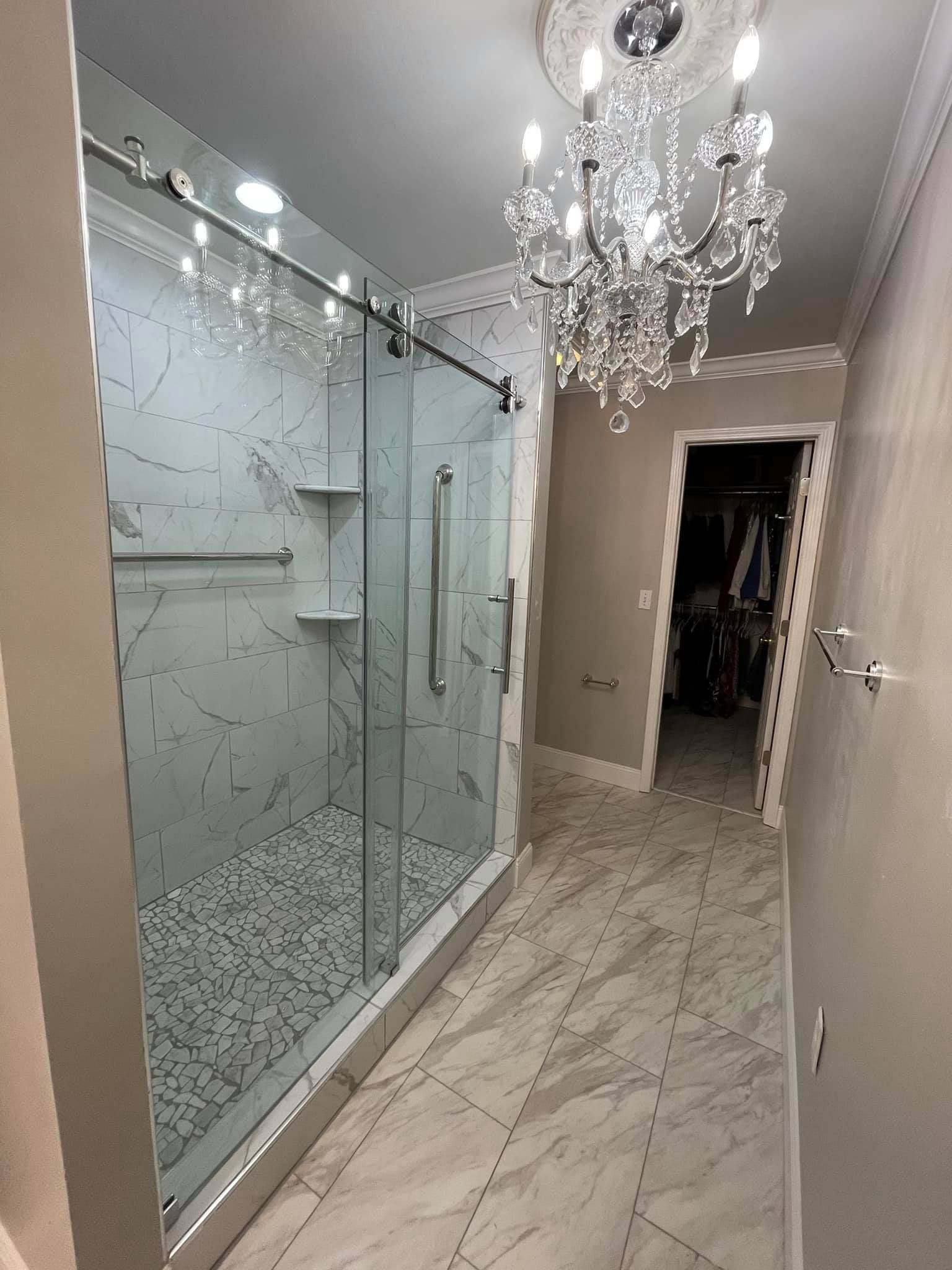 A bathroom with a walk in shower and a chandelier.
