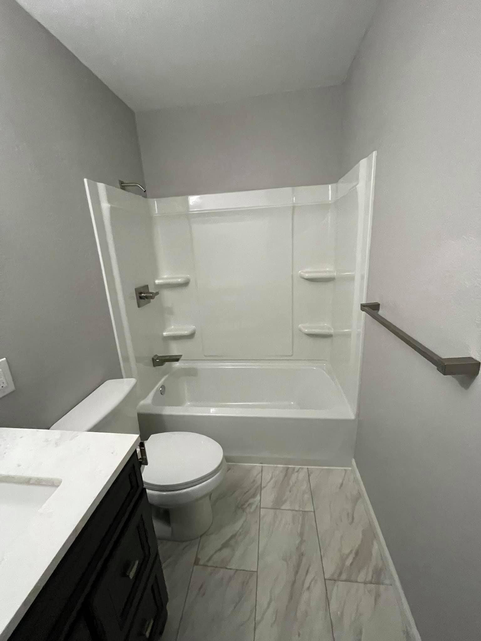 A bathroom with a toilet , sink , bathtub and shower.