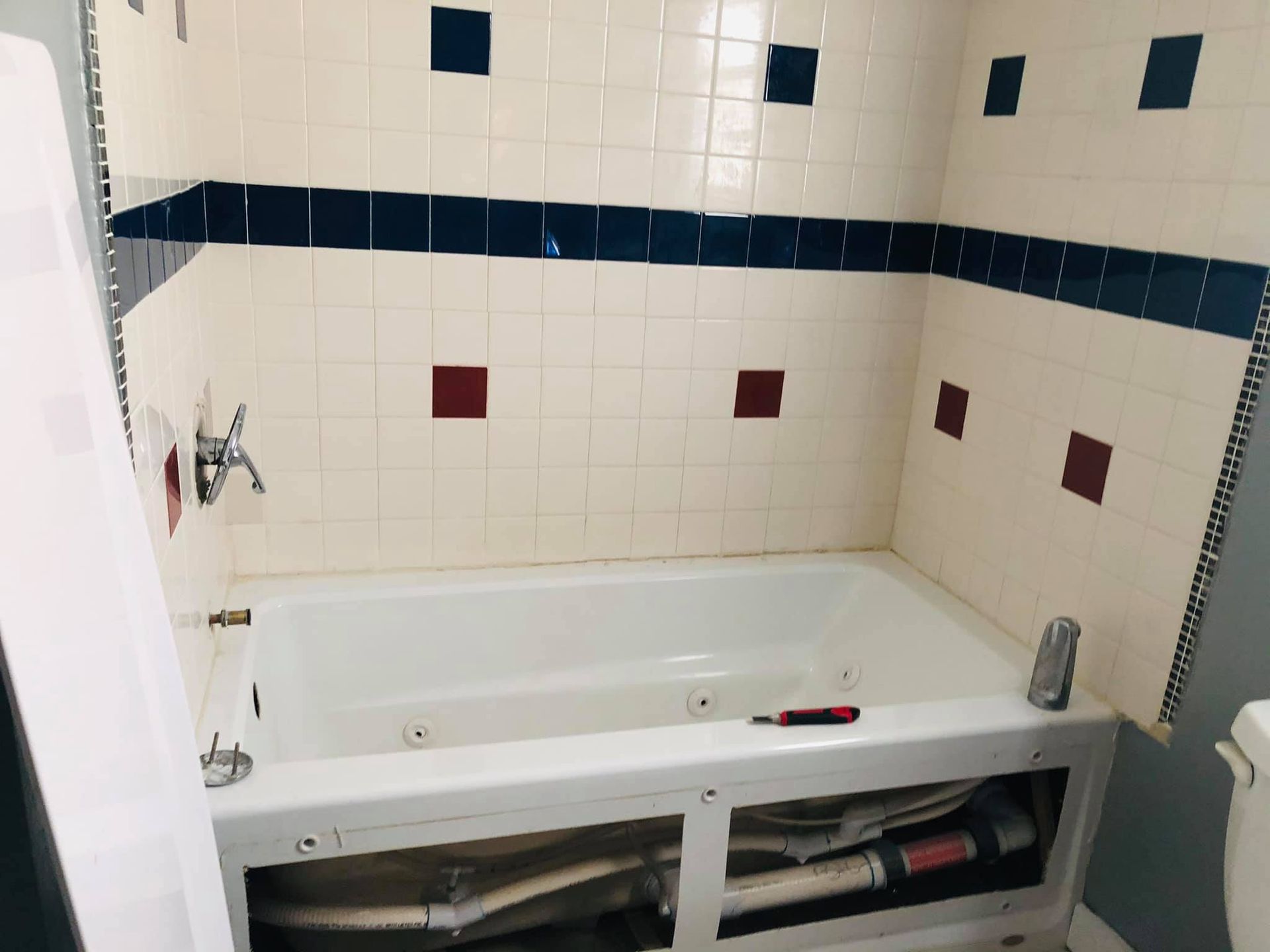 A bathtub in a bathroom with blue and white tiles