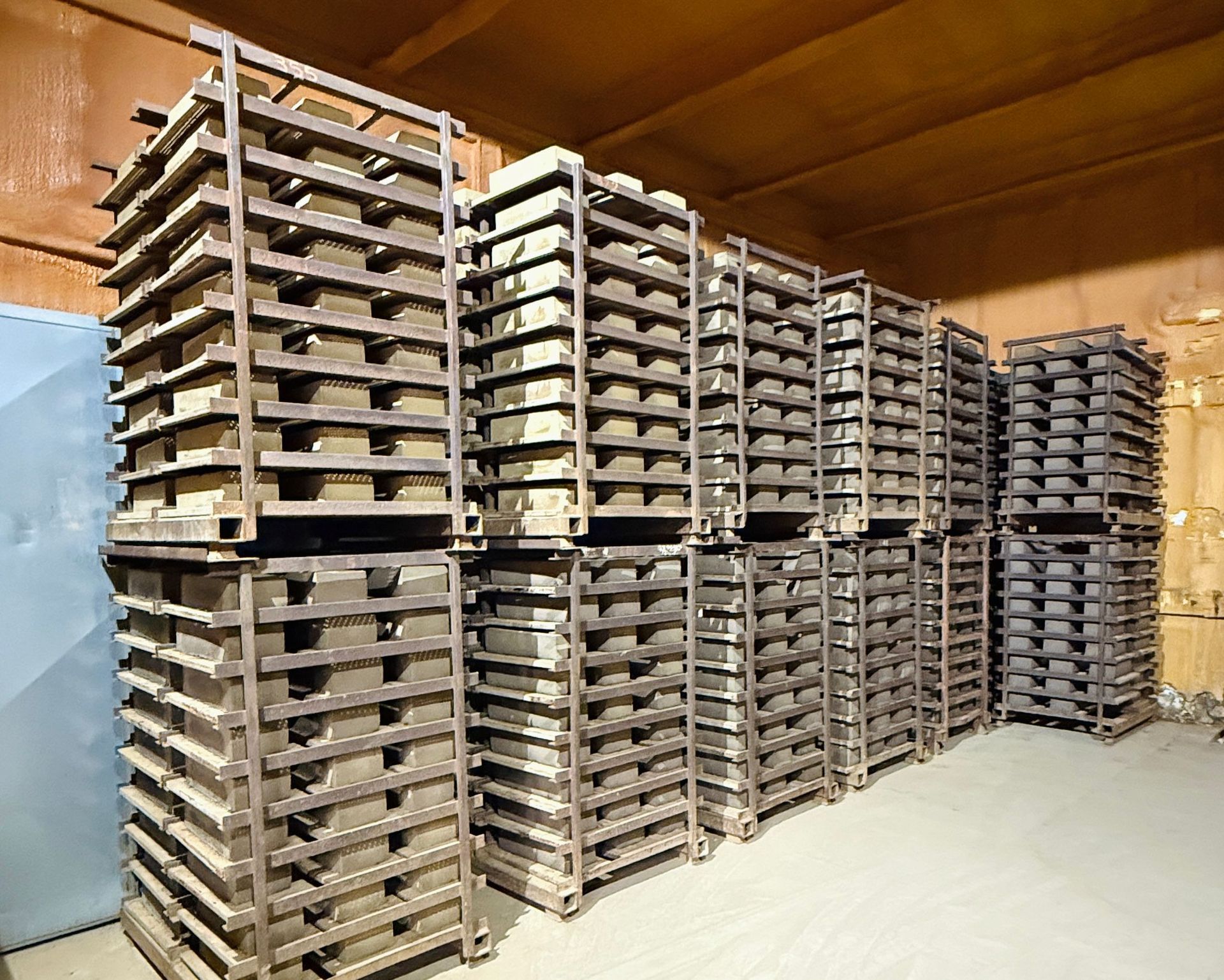 Warehouse with stacked metal trays on pallets in a large storage room