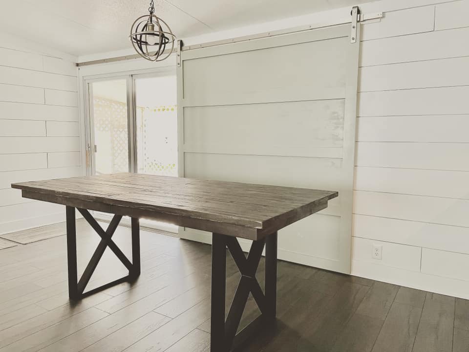 Dining room with rustic table and sliding door. White paneling and dark wood floor.