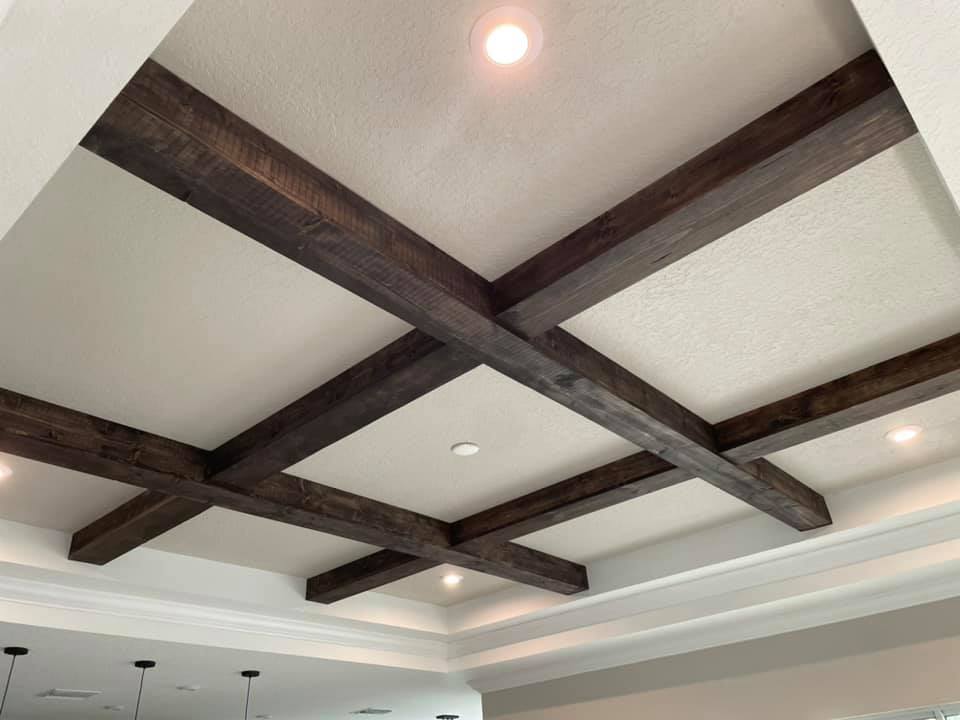 Dark wood beams crisscross a white ceiling with recessed lighting.