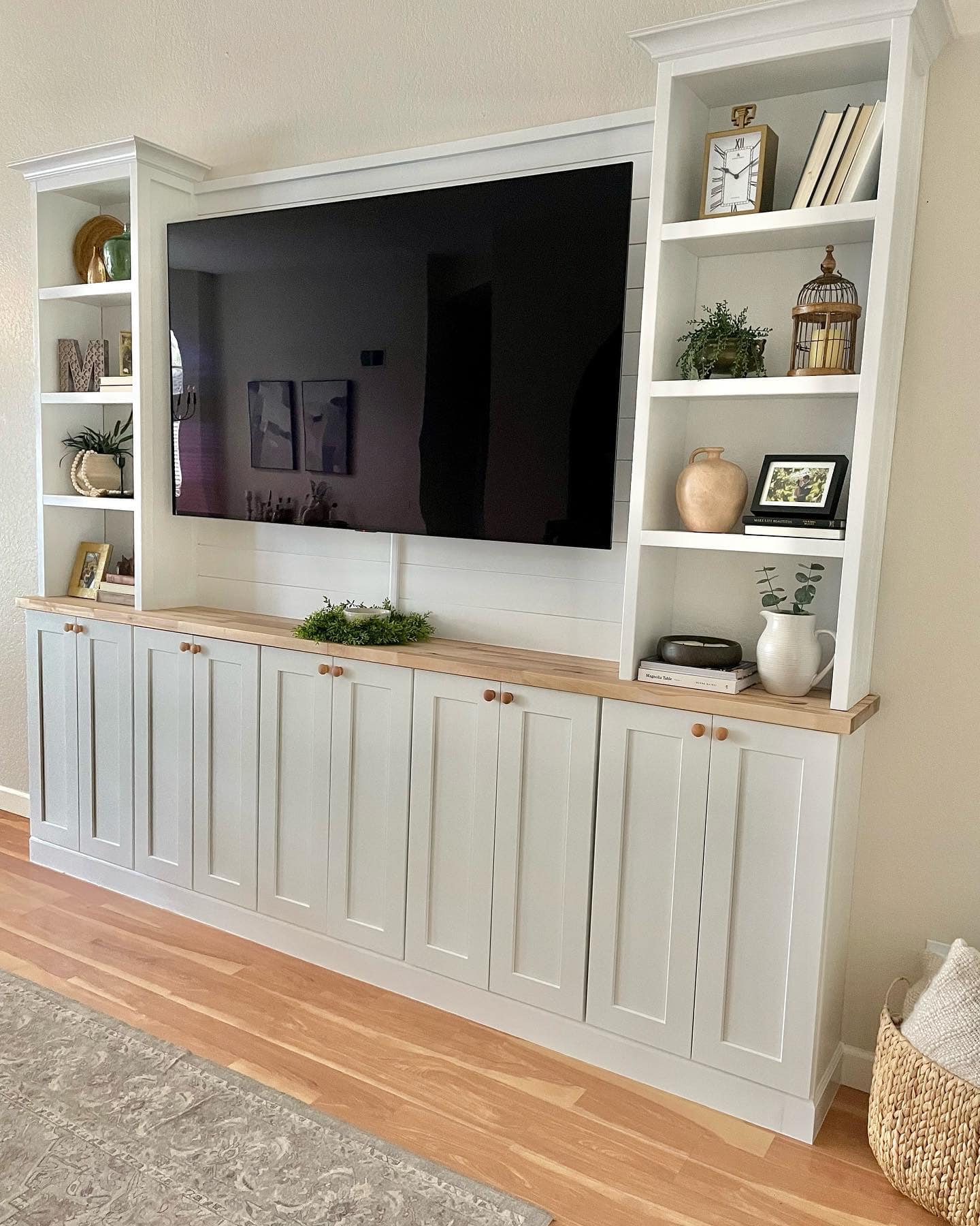 Built-in white cabinet with TV, shelving, and closed storage, set against a light wall.