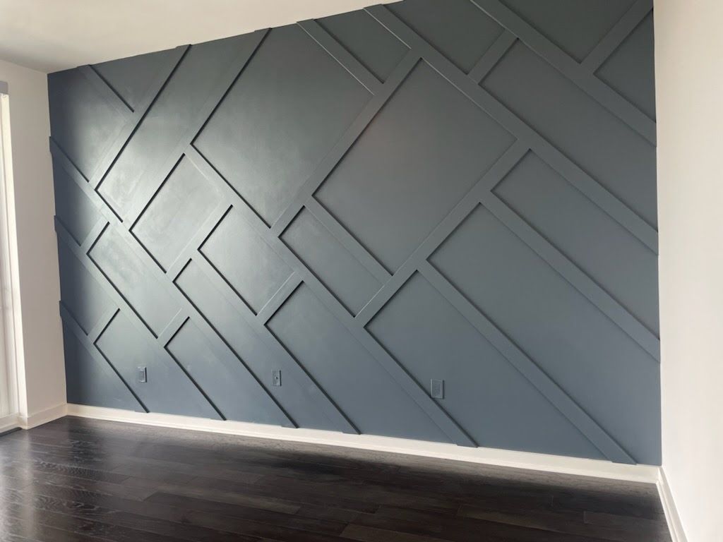 Dark blue accent wall with geometric wood paneling and dark wood floor.
