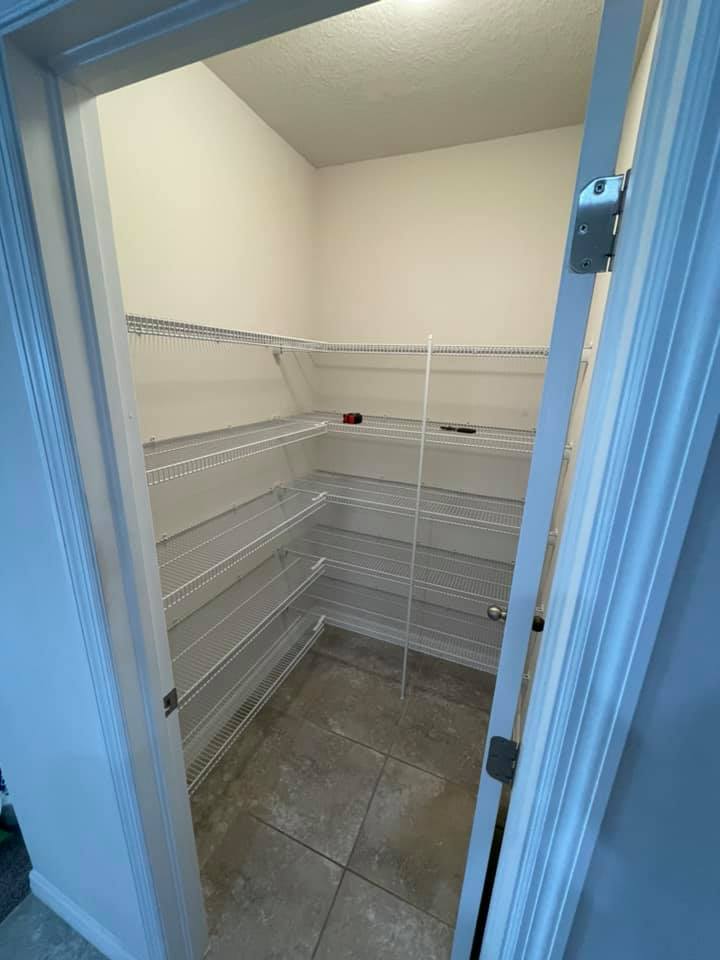 Empty pantry with wire shelves, gray tiled floor, and white walls.
