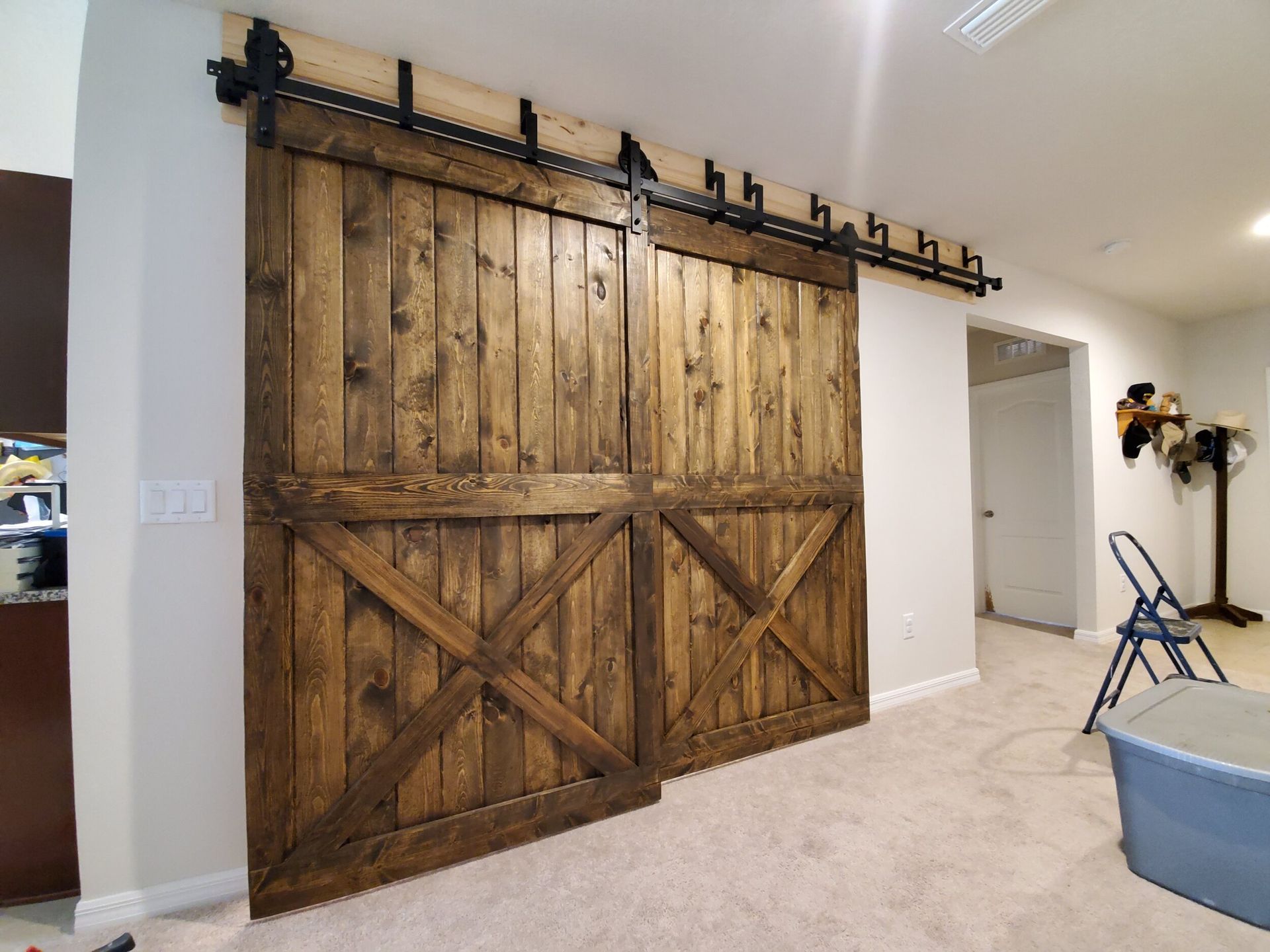 Two large, dark wooden barn doors with black hardware, in a hallway.