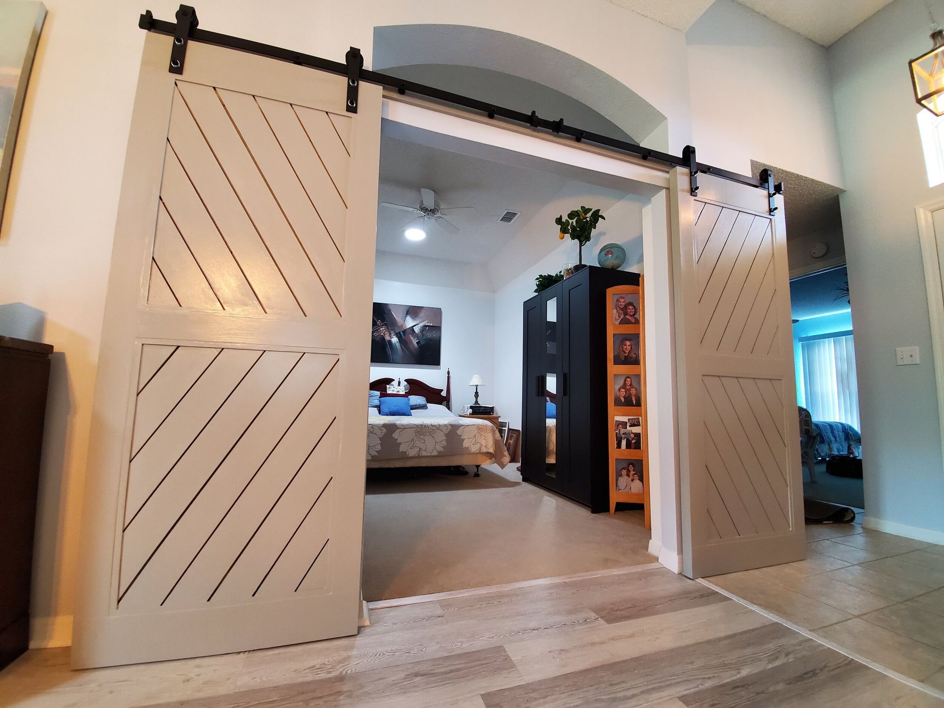Open barn doors leading to a bedroom. Light-colored wooden doors with a black track.