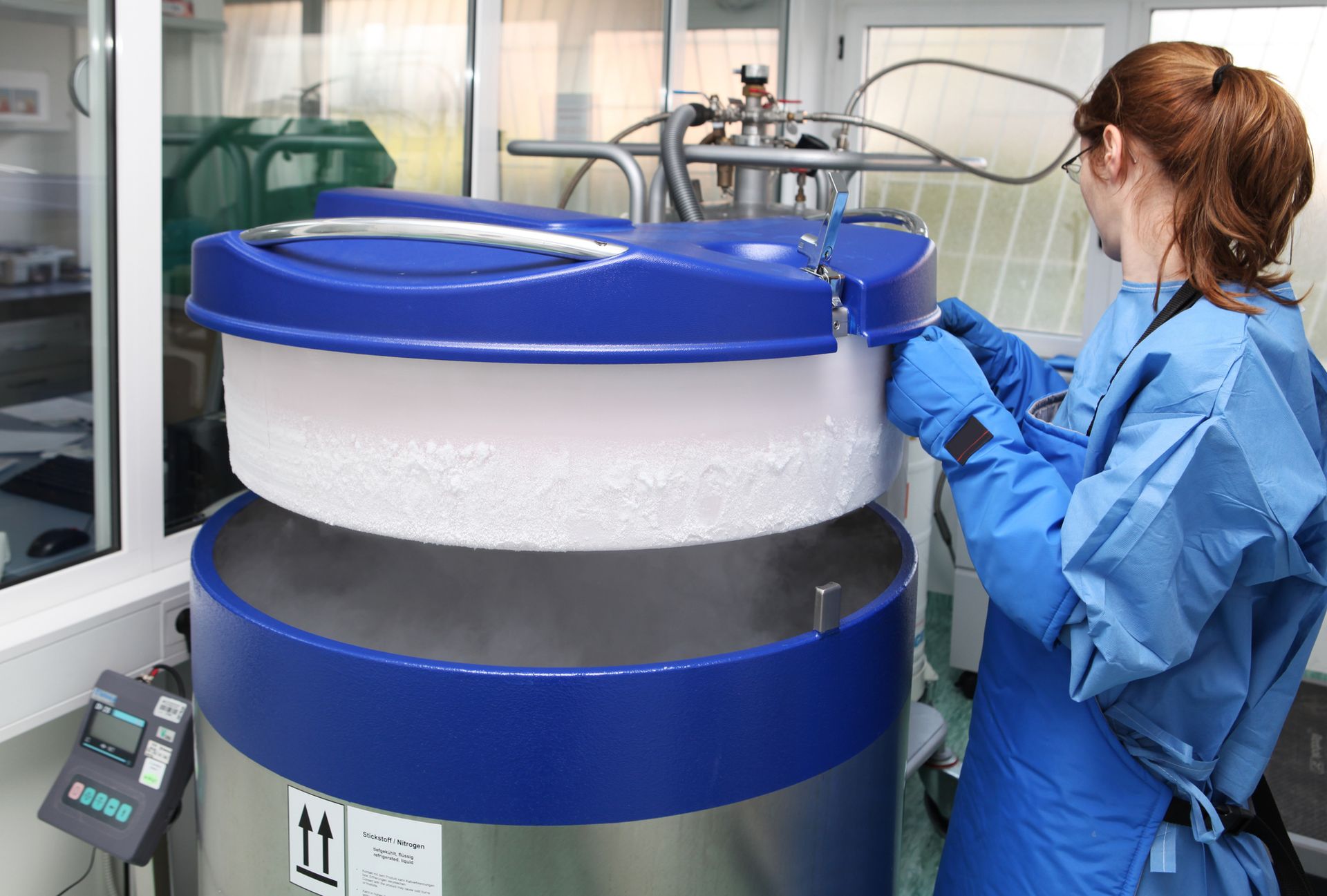 Technician in lab coat inspects water softening equipment in sterile lab environment.