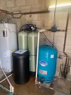 Water filtration and storage system in a utility room; includes a water heater, filtration tanks, and a pressure tank.